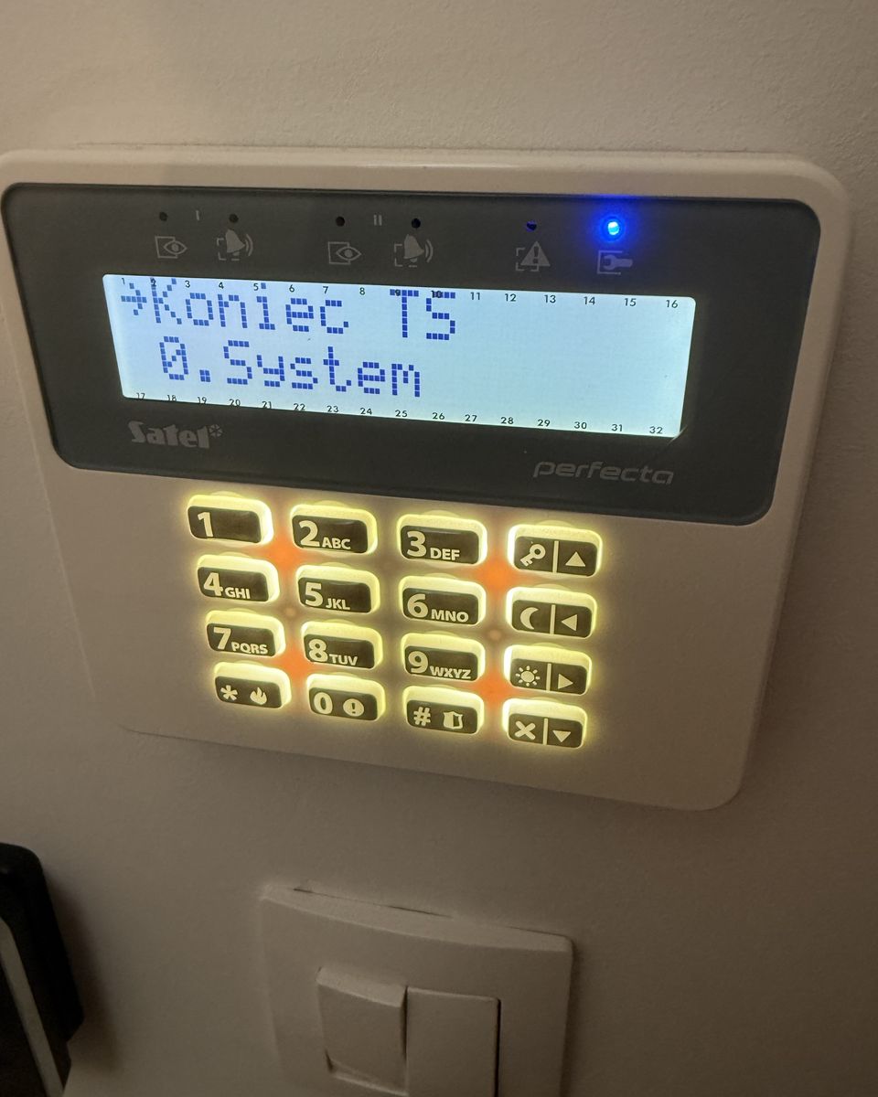 Manipulator systemu alarmowego z podświetloną klawiaturą i wyświetlaczem tekstowym, zamontowany na ścianie.