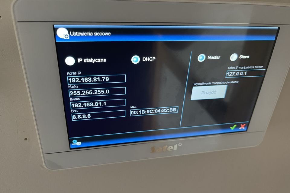 Dotykowy panel systemu alarmowego z ekranem ustawień sieciowych: adres IP, maska, brama i serwer DNS.