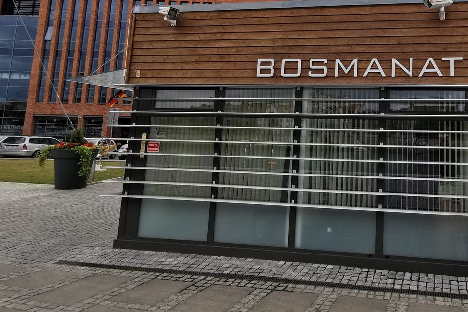 Pawilon Bosmanatu na bulwarach w Szczecinie, drewniana elewacja z napisem BOSMANAT; w tle biurowce.