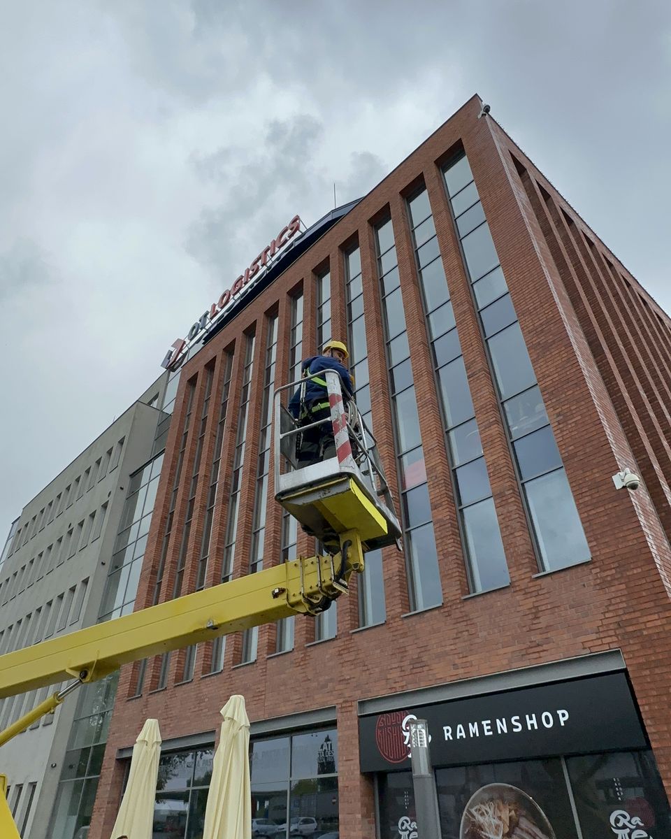 Technik w koszu podnośnika montuje kamerę na żywo na ceglanej elewacji biurowca Lastadia Office przy szczecińskich bulwarach.