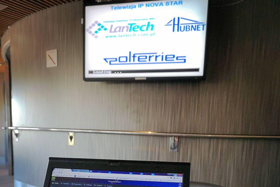 Telewizor na pokładzie wyświetla planszę telewizji IP, obok na stoliku laptop z programem ustawiania anteny satelitarnej.