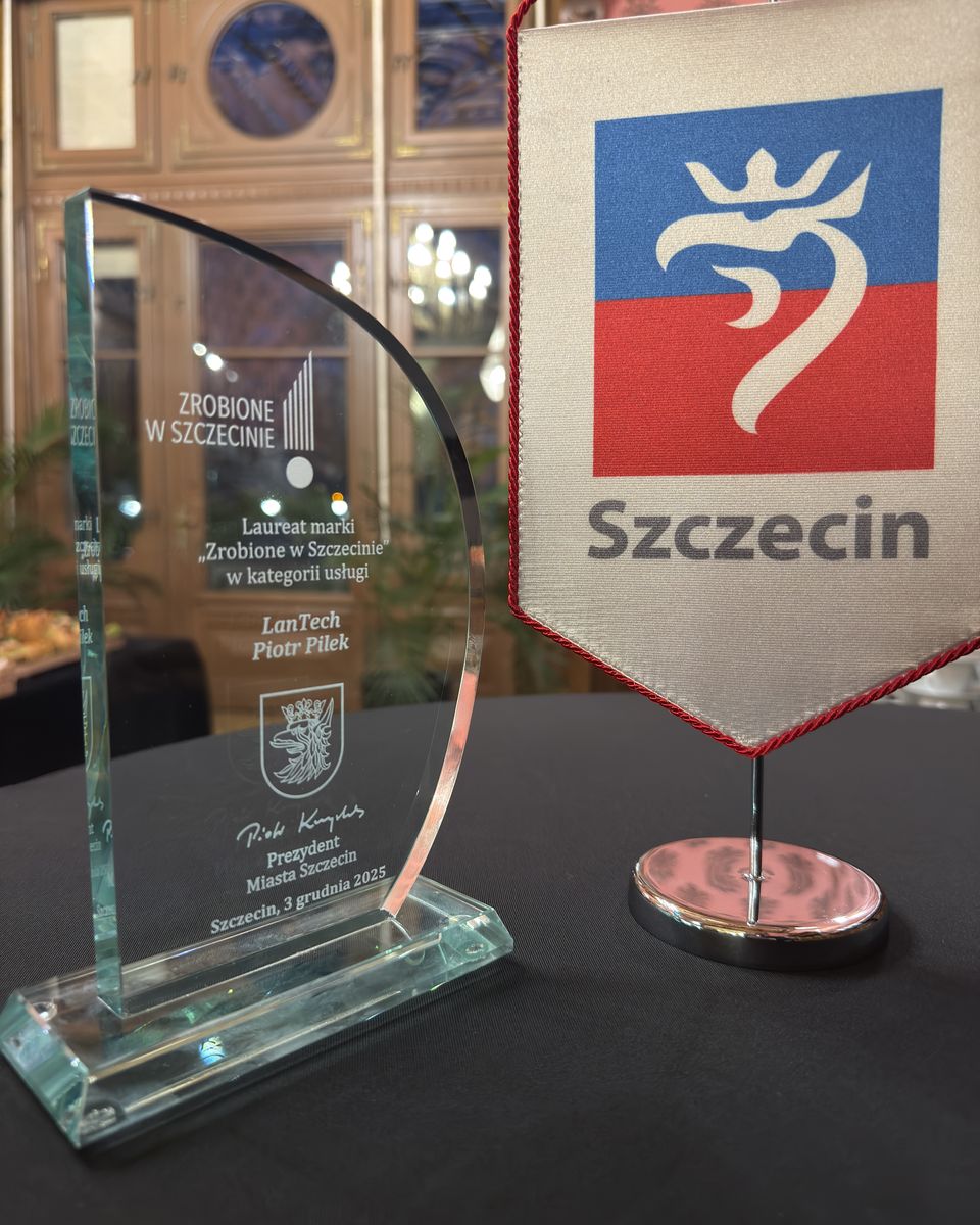 Szklana statuetka „Zrobione w Szczecinie” obok proporczyka z herbem i napisem Szczecin, na stole podczas gali.